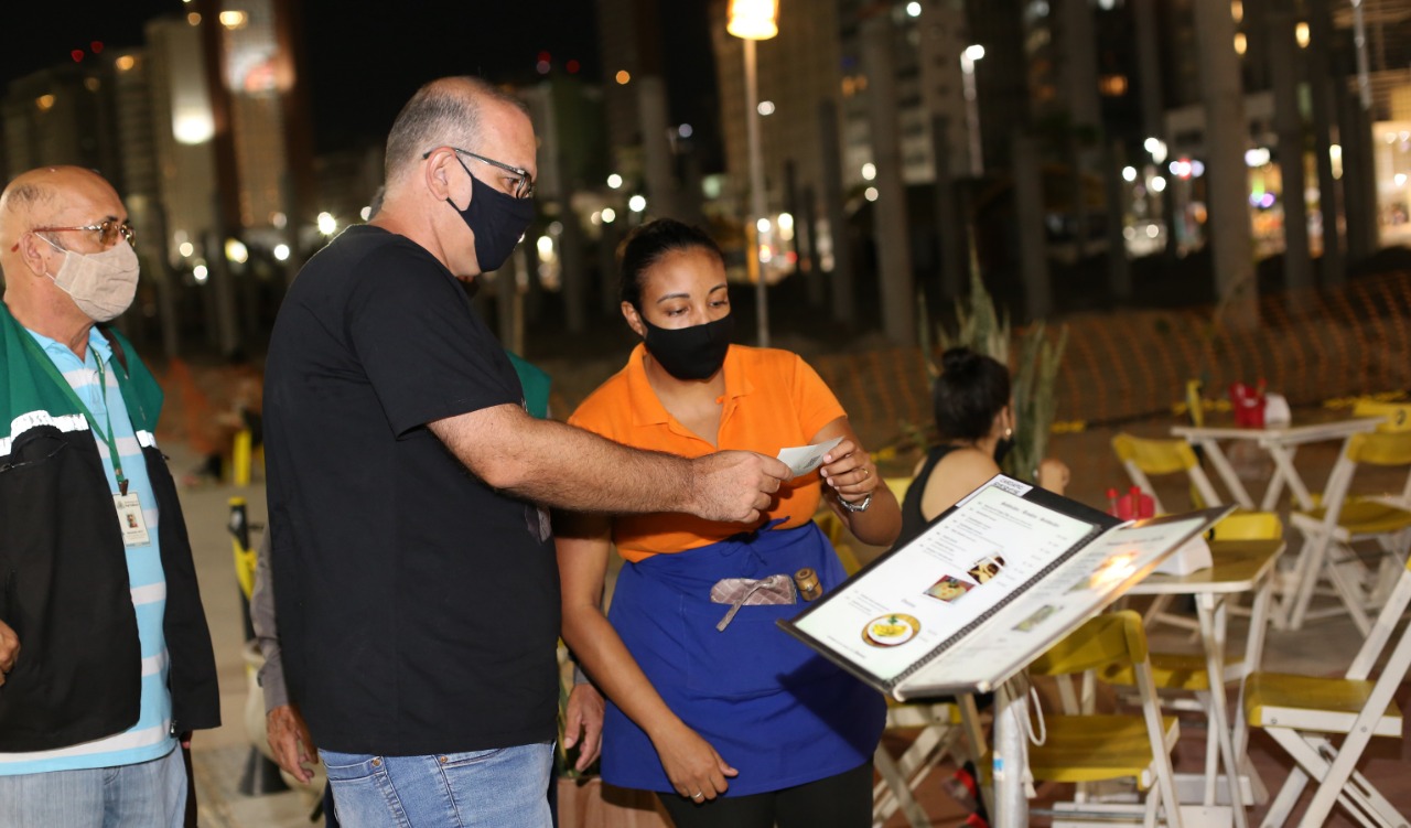 homem mostra o comprovante de vacinação na entrada de um bar